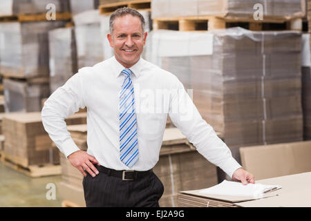 Patron souriant leaning on stack de cartons Banque D'Images