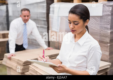 Warehouse Manager writing on clipboard Banque D'Images