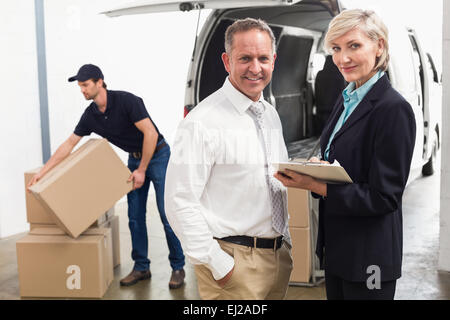 Les gestionnaires smiling at camera avec chauffeur de livraison derrière Banque D'Images