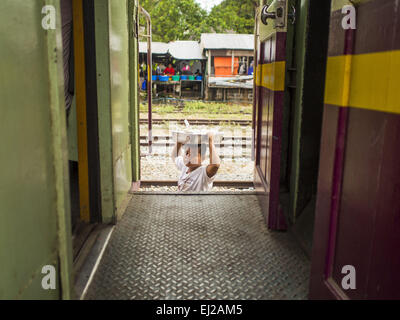 Prachinburi, Prachinburi, Thaïlande. Mar 20, 2015. Un enfant travaillant comme vendeur de voitures dans la marche entre la gare de Prachinburi. Il vend des collations pour les passagers de 3e classe d'un train pour Kabin Buri. Les chemins de fer de l'état de la Thaïlande (SRT), créée en 1890, exploite 4 043 kilomètres de voie à voie métrique qui atteint la plupart des régions de la Thaïlande. Une bonne partie de la piste et de nombreux trains sont souvent mal entretenus et les trains sont en retard. Accidents et d'incidents sont également monnaie courante. Les gouvernements successifs, y compris l'actuel gouvernement militaire, ont promis d'améliorer les services ferroviaires. Banque D'Images