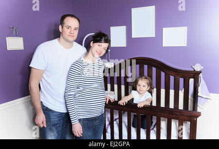 Famille à l'intérieur de la chambre du bébé avec bébé dans un lit bébé. Banque D'Images