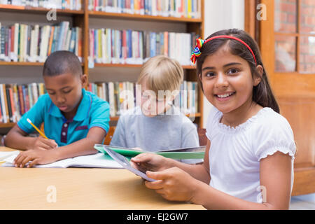 Cute élève using tablet computer in library Banque D'Images