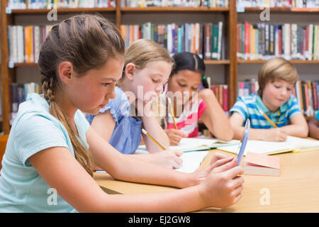 Cute élève using tablet computer in library Banque D'Images