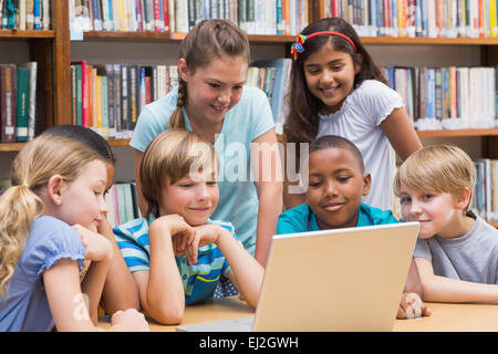 Cute pupils using tablet computer in library Banque D'Images