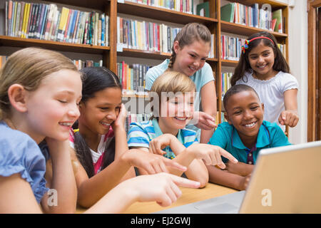 Cute pupils using tablet computer in library Banque D'Images