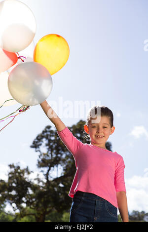 Happy little girl holding balloons Banque D'Images