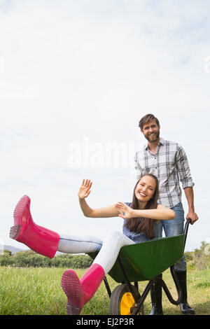 L'homme en poussant son amie dans une brouette Banque D'Images