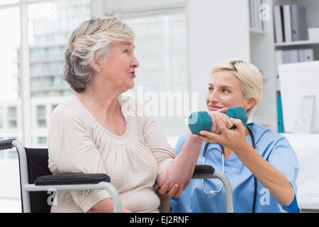 Nurse patient tandis que l'aider à la levée de l'haltère Banque D'Images