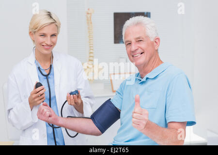 Showing Thumbs up patient médecin alors que contrôler sa pression artérielle Banque D'Images