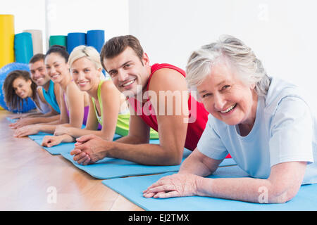 Senior woman with allongé sur des tapis d'entraînement à la salle de sport Banque D'Images