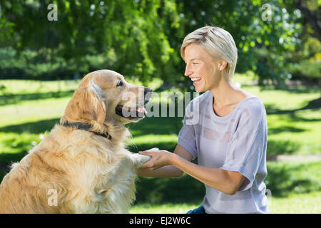 Jolie blonde jouant avec son chien dans le parc Banque D'Images