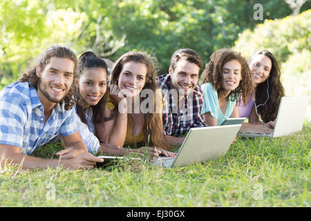 Smiling friends dans le parc à l'aide de Tablet PC et ordinateur portable Banque D'Images