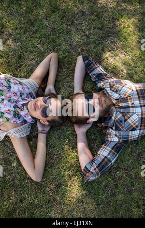 Jeune couple lying on grass smiling at camera Banque D'Images