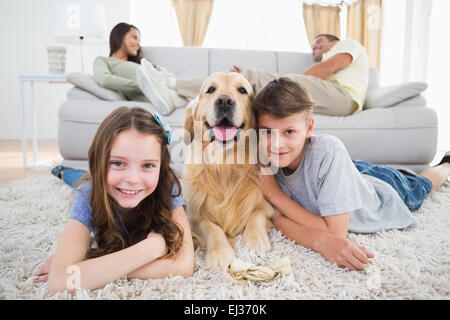 Frères et sœurs couchant avec chien tandis que les parents se reposant sur canapé Banque D'Images