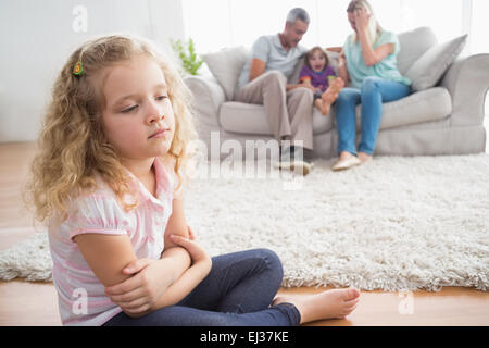 Upset girl sitting on floor tandis que les parents bénéficiant d'avec le frère Banque D'Images