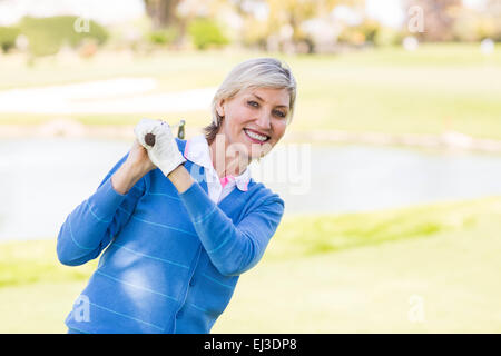 Femme debout tenant son club golfeur smiling Banque D'Images