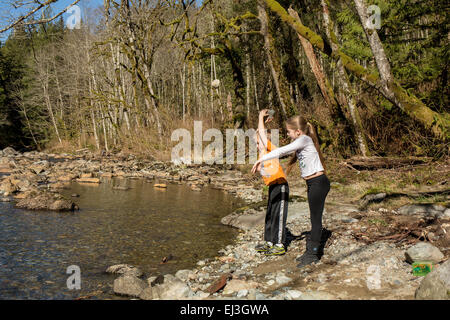 Neuf ans, fille et garçon de sept ans jeter des pierres dans la rivière Snoqualmie près de North Bend, Oregon, USA Banque D'Images