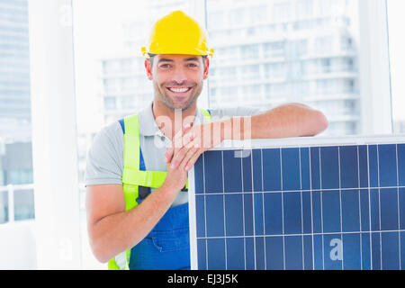 Happy handyman avec panneau solaire in bright office Banque D'Images