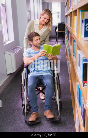 Smiling étudiante handicapée avec camarade in library Banque D'Images