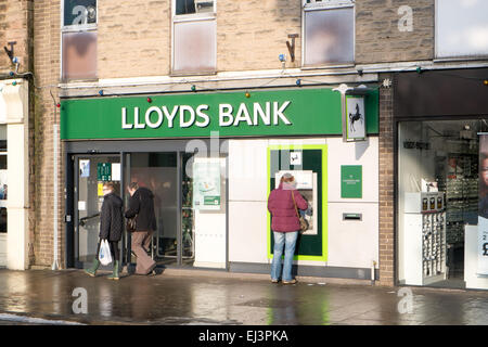 Femme anglaise utilisant le distributeur automatique de cashpoint dans une succursale de banque lloyds à Matlock, Derbyshire, Angleterre Banque D'Images