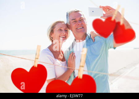 Image composite de happy senior couple selfies posant pour une Banque D'Images