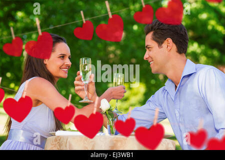 Image composite de couple avec des flûtes à champagne sitting at outdoor cafÃ© Banque D'Images