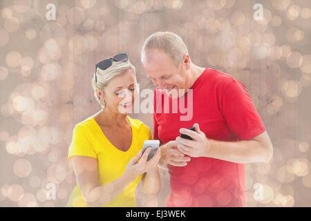 Composite image of happy mature couple looking at smartphone ensemble Banque D'Images