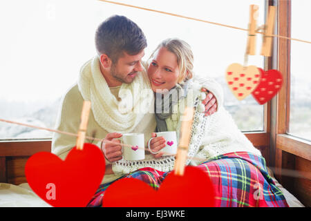 Image composite du couple aimant en hiver l'usure avec fenêtre contre tasses Banque D'Images