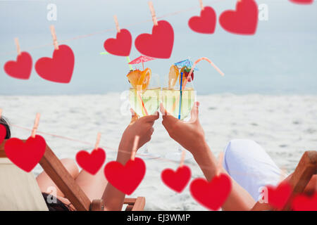 Image composite du couple clinking glasses of cocktail on beach Banque D'Images