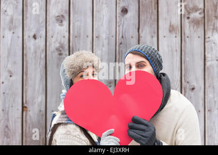 Composite image jeune couple dans des vêtements chauds holding red heart Banque D'Images