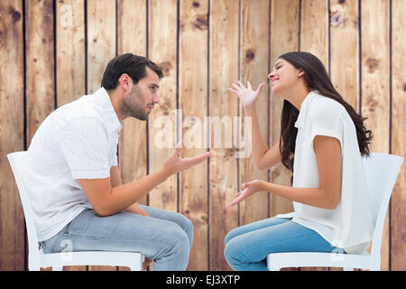 Image composite de couple assis sur des chaises en faisant valoir Banque D'Images