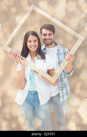 Image composite de happy young couple holding photo frame Banque D'Images