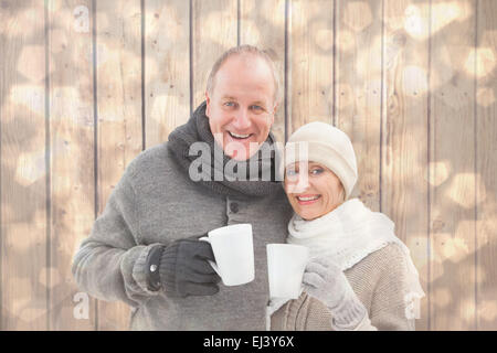 Image composite de mature woman in winter clothes holding mugs Banque D'Images