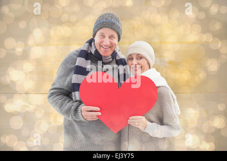 Image composite de mature woman in winter clothes holding red heart Banque D'Images