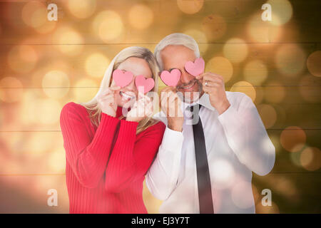 Image composite de silly couple holding cœurs sur les yeux Banque D'Images