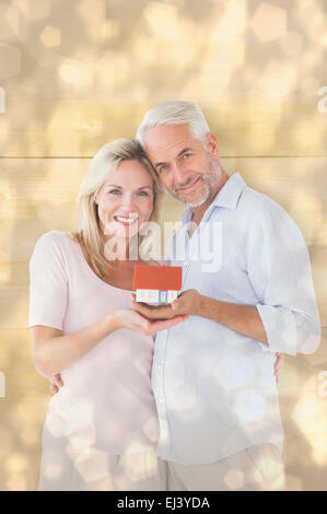 Image composite de l'heureux couple holding modèle miniature house Banque D'Images