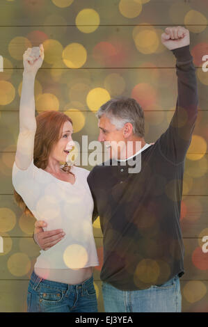 Image composite de casual couple cheering and smiling Banque D'Images