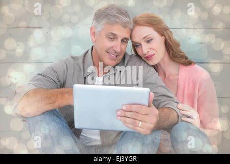 Image composite de casual couple assis à l'aide de tablet Banque D'Images