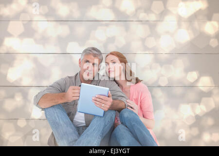 Image composite de casual couple assis à l'aide de tablet Banque D'Images