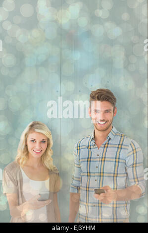 Image composite de beau couple à l'aide de leurs smartphones Banque D'Images