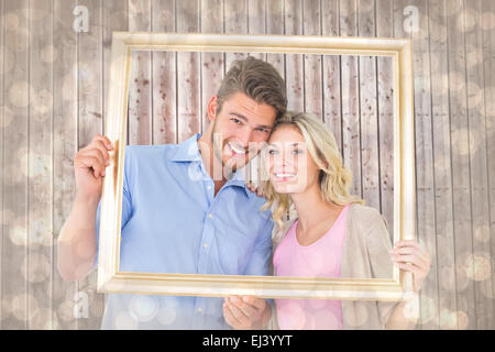 Composite image of young couple holding photo frame Banque D'Images