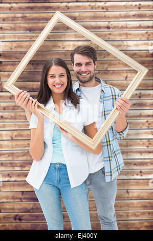 Image composite de happy young couple holding photo frame Banque D'Images