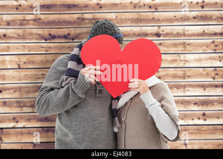 Image composite de mature woman in winter clothes holding red heart Banque D'Images