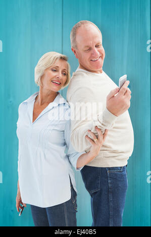 Composite image of happy mature couple looking at smartphone ensemble Banque D'Images