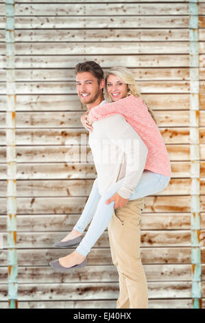 Image composite de handsome man giving piggy back pour sa petite amie Banque D'Images