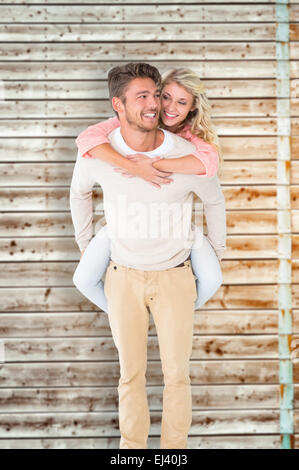 Image composite de handsome man giving piggy back pour sa petite amie Banque D'Images