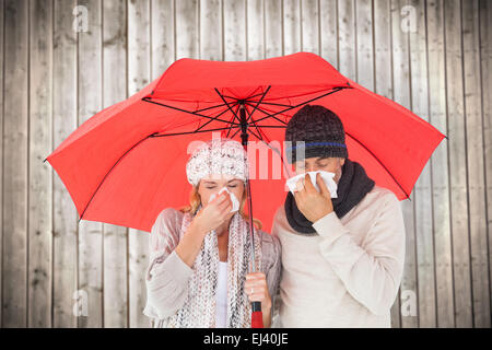 Image composite de couple in winter fashion éternuements under umbrella Banque D'Images