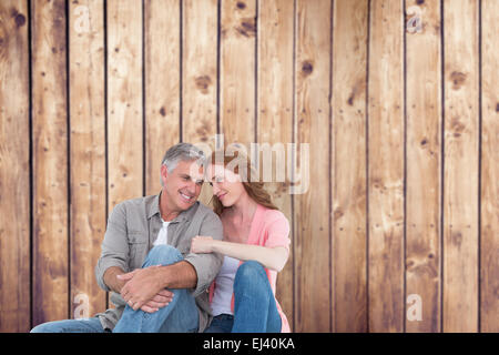 Image composite de casual couple sitting and smiling Banque D'Images