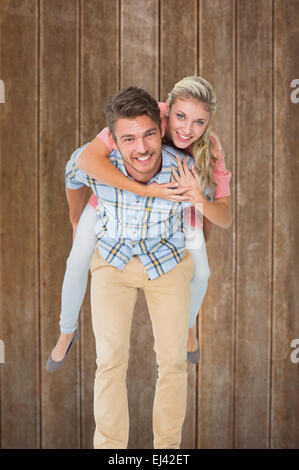 Image composite de handsome man giving piggy back pour sa petite amie Banque D'Images