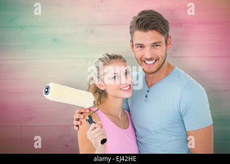 Image composite du jeune couple hugging and holding paint roller Banque D'Images